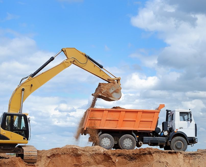 Bagger ladet Sand in einen Muldenkipper